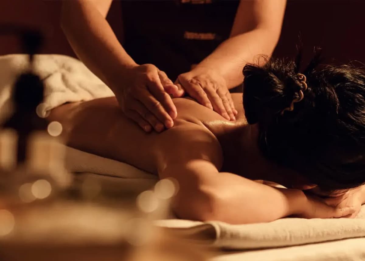 A therapist giving a massage in a warm, dim treatment room