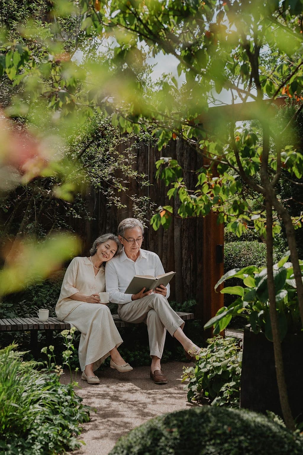 An older couple reading together in a leafy garden