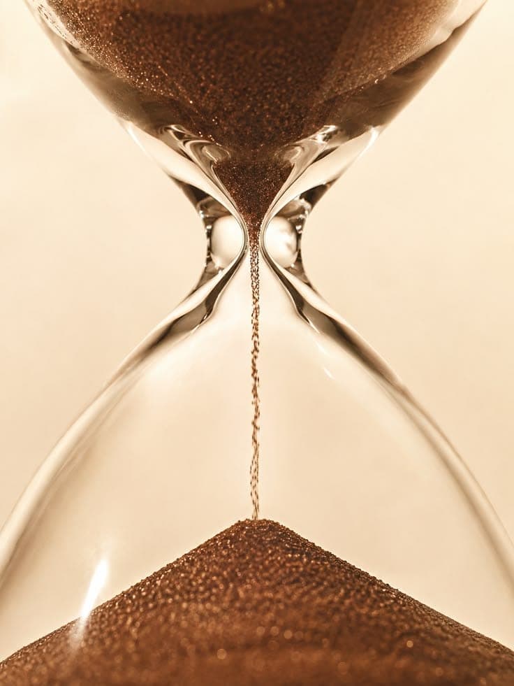 An hourglass with sand falling in warm light