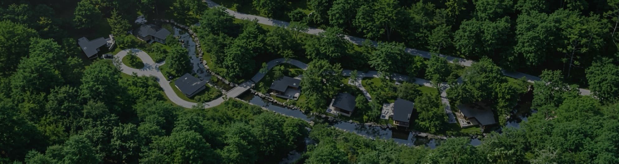 Aerial view of VELA — private pool villas and a wellness club beside a quiet canal, among coconut palms in Khao Lak, Phang Nga